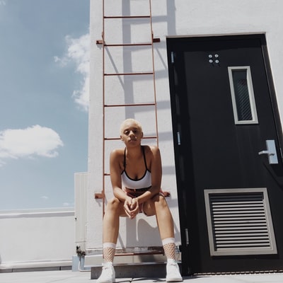 女人在白人和黑人运动胸罩坐在橙色金属消防梯
